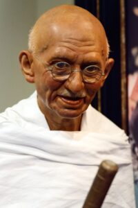 ein Foto von Mahatma Gandhi in weißer Kleidung mit einem Stock in der Hand