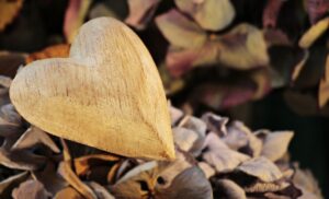 ein Herz aus Holz liegt auf einem Laubhaufen