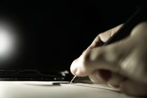 Eine Hand hält einen Stift und schreibt damit auf Papier.