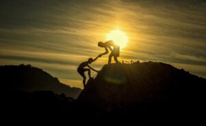 eine Person hilft der anderen dabei, auf einen Berg zu klettern.
